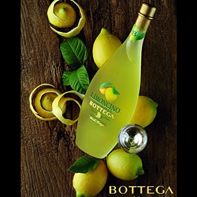 Garrafa de licor Limoncino Bottega com limões e cascas sobre madeira