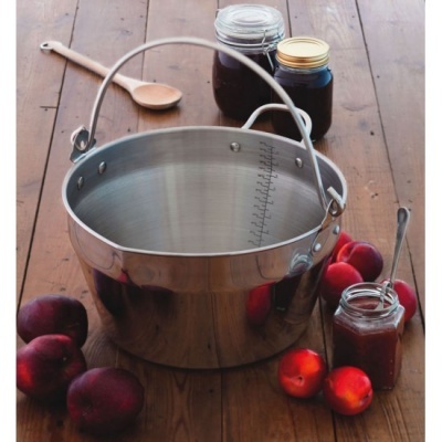 Balde metálico prateado com alça e graduação interior junto com frutas e compotas em mesa de madeira