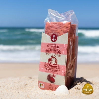 Pacote de bolachas de beterraba na areia com mar ao fundo