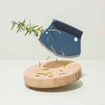 Fatiador de ervas azul com lâmina em tábua de madeira clara