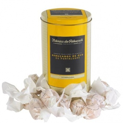 Lata amarela com rótulo preto e dourado e rebuçados embrulhados em papel branco