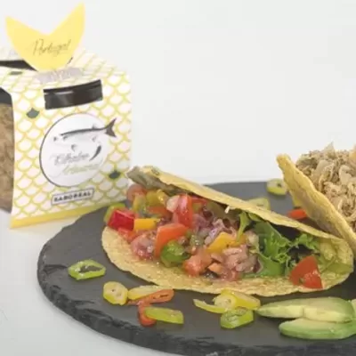 Tortilhas recheadas com salada e carne ao lado de embalagem amarela com padrão de escamas.