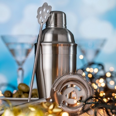 Conjunto de bar em aço inoxidável com coqueteleira, colher, coador e luzes de Natal ao fundo