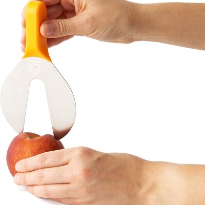 Faca descascadora laranja a cortar pêssego em fundo branco