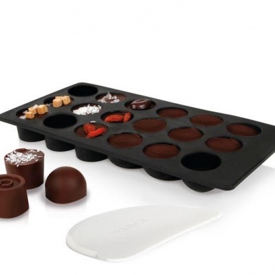 Forma de silicone preta para bombons com espátula e bombons.