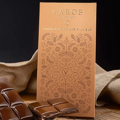Barra de chocolate de leite CAROB com embalagem rosa e padrão decorativo floral