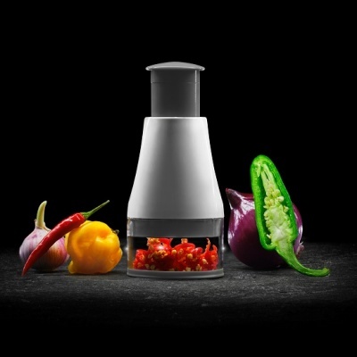 Triturador manual branco com pimentas coloridas e cortadas ao redor