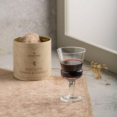 Lata de biscoitos sabor vinho e canela com taça de vinho