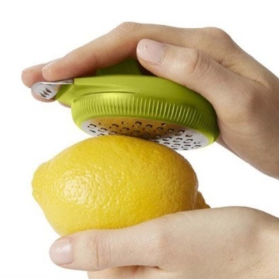 Raladora manual verde a ralar limão amarelo nas mãos