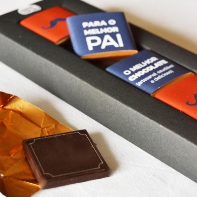 Caixa com chocolates quadrados embrulhados, um desembrulhado em primeiro plano