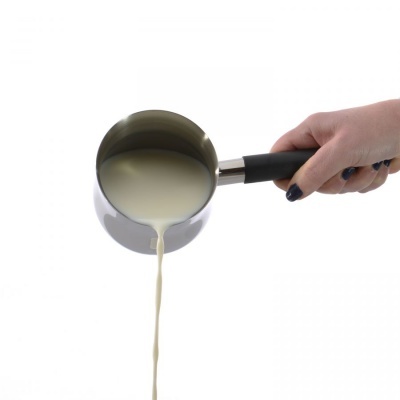 Panela cinzenta com leite a ser derramado, segurada por uma mão