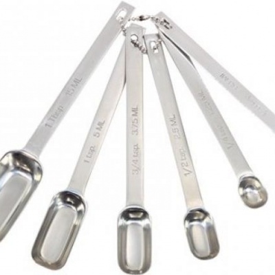 Conjunto de cinco colheres medidoras em aço inoxidável com marcas de medidas gravadas nas pegas.