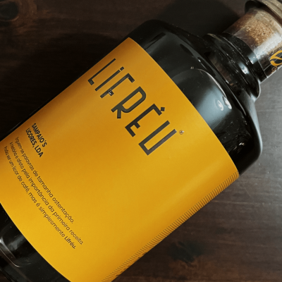 Garrafa de vidro com rótulo amarelo e tampa de cortiça sobre madeira