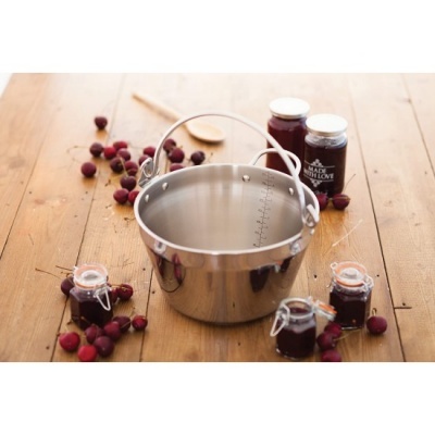 Panela de metal prateada com frascos de compota e frutos vermelhos