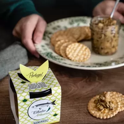 Embalagem de papel verde e branco com texto e bolachas redondas com pasta em prateleira de madeira
