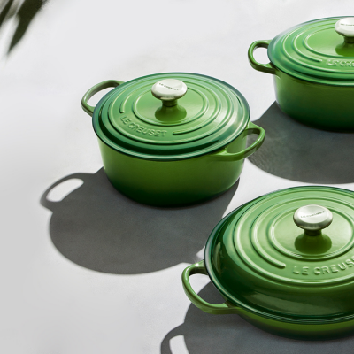 Três panelas verdes Le Creuset em ferro fundido com tampas e botões brancos
