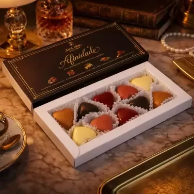 Caixa de chocolates sortidos em forma de coração sobre mesa de mármore, com objetos antigos ao redor