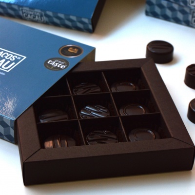 Caixa azul de chocolates escuros com nove peças em bandeja preta
