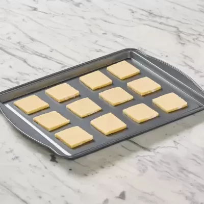 Tabuleiro com pedaços quadrados de massa crua sobre superfície de mármore