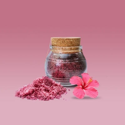 Frasco de vidro com tampa de cortiça e sal rosa ao lado com flor de hibisco