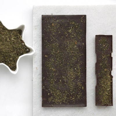 Barras de chocolate escuro com ervas verdes e tigela branca com ervas