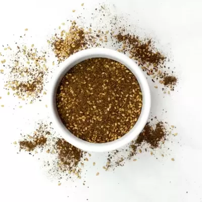 Pote branco com especiarias castanhas e douradas sobre fundo branco