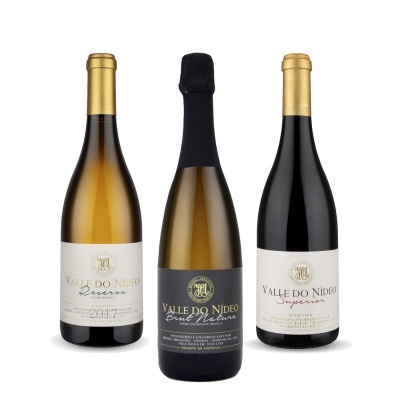 Três garrafas de vinho VALLE DO NÍDEO com rótulos branco e preto e rolhas douradas e preta