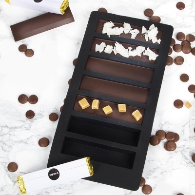 Forma de silicone com barras de chocolate e pedaços de coco e caramelo
