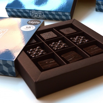 Caixa azul de chocolates variados Pedaços de Cacau com texto e selos de qualidade