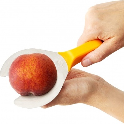 Instrumento de corte amarelo a cortar pêssego vermelho e amarelo com fundo branco.