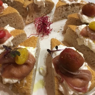 Fatias de pão com creme, presunto e tomates cherry coloridos num prato redondo