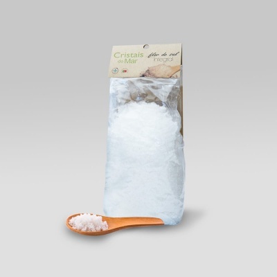 Saco de cristais de sal branco com rótulo e colher de madeira com sal