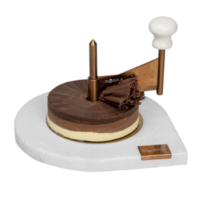 Dispositivo cortador redondo de chocolate com lâmina metálica e manivela branca sobre base branca.