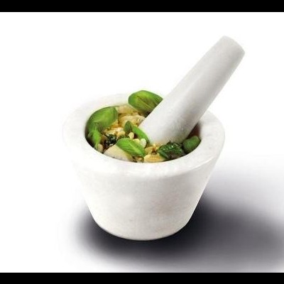 Pilão de mármore branco com almofariz cheio de folhas e sementes verdes