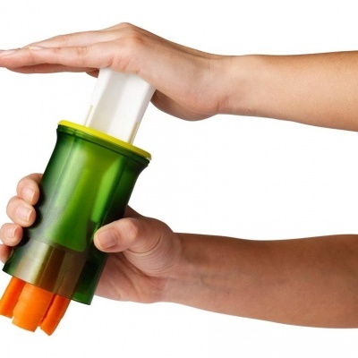 Dispositivo manual verde para cortar legumes com pedaços de cenoura