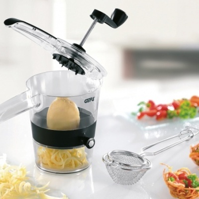 Ralador de queijo manual GEFU em plástico transparente e preto numa cozinha