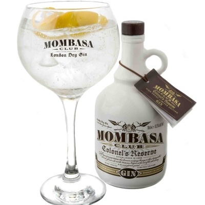 Garrafa branca de gin Mombasa Club com copo de gin cheio ao lado