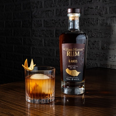 Garrafa e copo de rum âmbar com decoração em mesa de madeira