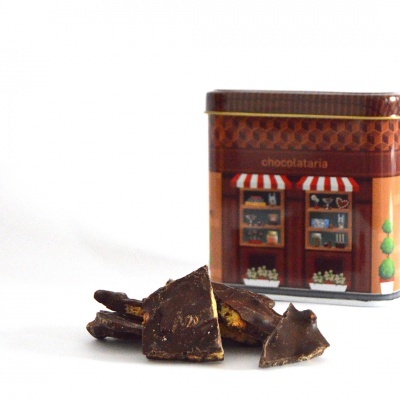 Pedaços de chocolate escuro e caixa metálica decorativa com ilustração de loja