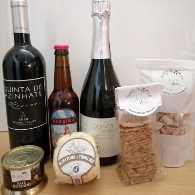Produtos gourmet incluindo vinho tinto, cerveja, espumante, paté, queijo, crackers e doces
