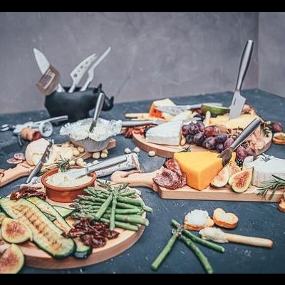 Tábuas de queijos, frutas, enchidos e vinho em superfície escura