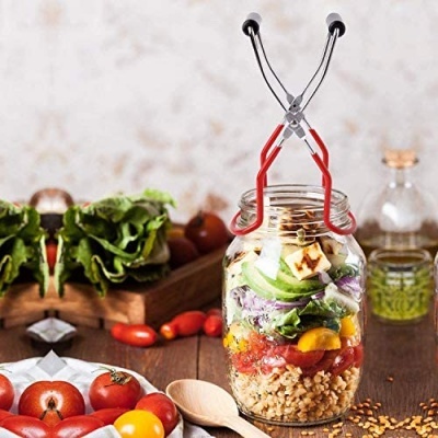 Frasco de vidro com salada em camadas e suporte metálico em mesa de madeira com legumes