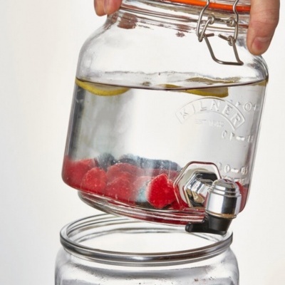 Recipiente de vidro com água, limão e framboesas com torneira