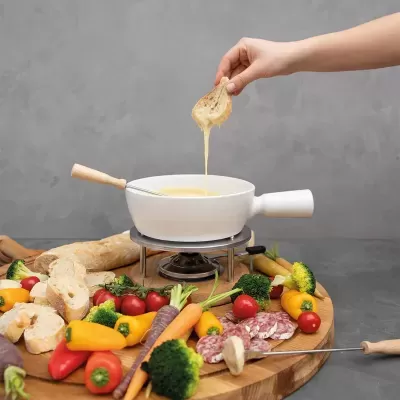 Conjunto de fondue com queijo derretido e tábuas de legumes, pão e carne fatiada