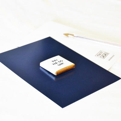 Chocolate quadrado com texto 'PAI HÁ SÓ UM!' sobre superfície azul e caneta