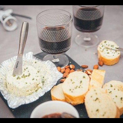 Tábua com queijo cremoso, pão, amêndoas e copos de bebida escura