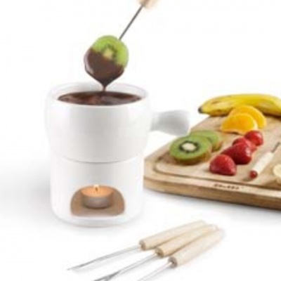 Conjunto de fondue branco com chocolate e frutas para mergulhar.