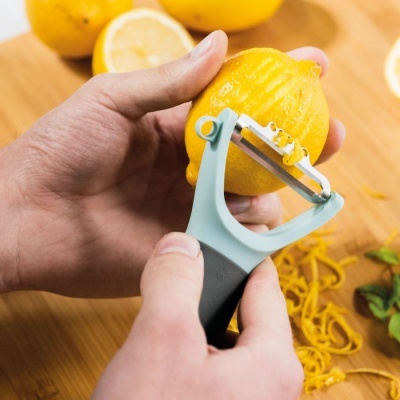 Descascador removendo casca de limão amarelo com limões e cascas ao fundo