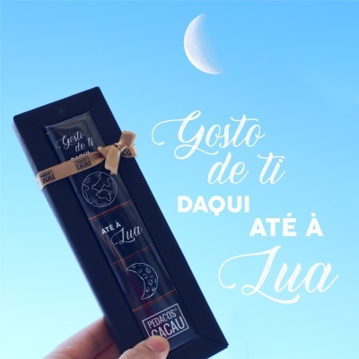 Barra de chocolate com embalagem preta com texto e ilustrações da lua, céu azul e lua crescente no fundo