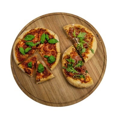 Tabuleiro redondo de madeira com duas pizzas variadas com folhas verdes.